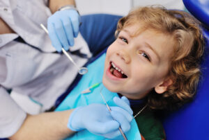 Child in a dentist chain and dentist holding various dental tools. 