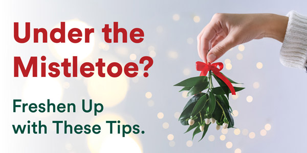 Hand holding mistletoe with the text Under the Mistletoe? Freshen Up with These Tips.